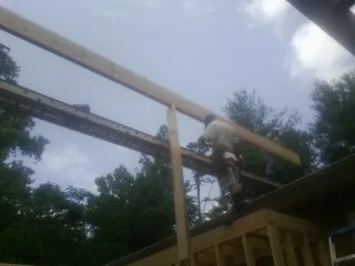 Carpenter setting a ridge beam over a new addition frame — Ice Dam Removal by Roofing Brothers in Methuen