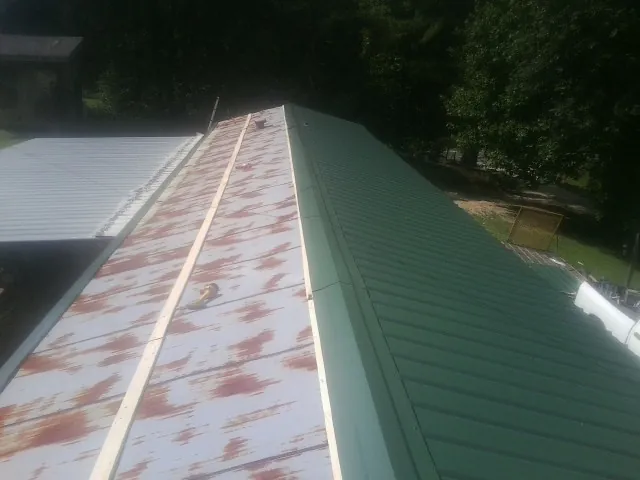 Old rusted panels beside newly installed green metal roofing — Wind Damage Roof Repair by Roofing Brothers in Methuen