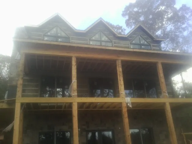 Dormers and porch framing on a large log home under construction — Roof Coating work by our crew in Methuen