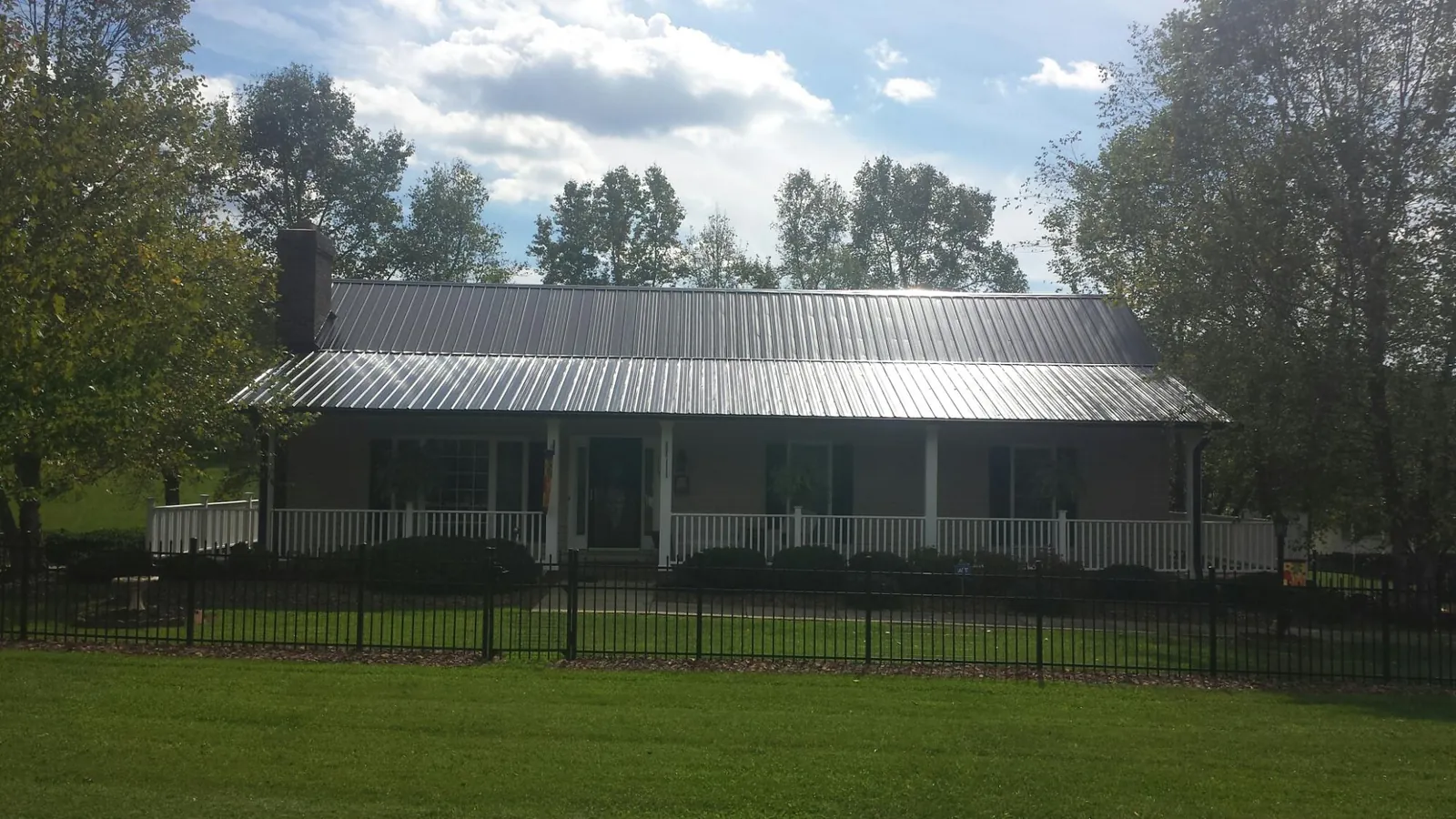 Gray metal roof on a brick ranch with a full width front porch — Gutter Guard Installation work by our crew in Methuen