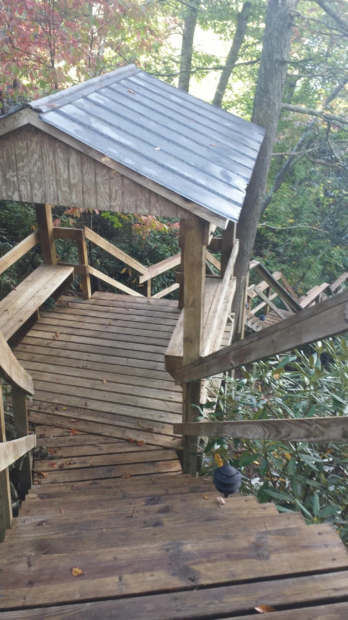 Metal roofed shelter over wooden steps on a wooded walkway — Skylight Repair & Installation work by our crew in Methuen