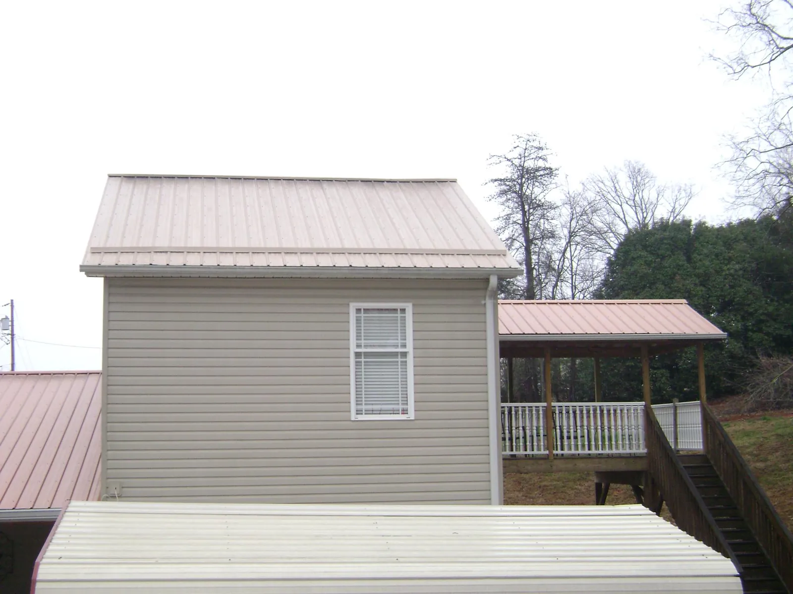 Tan metal roofs on a two story addition and attached porch, from a Roof Replacement job in Methuen