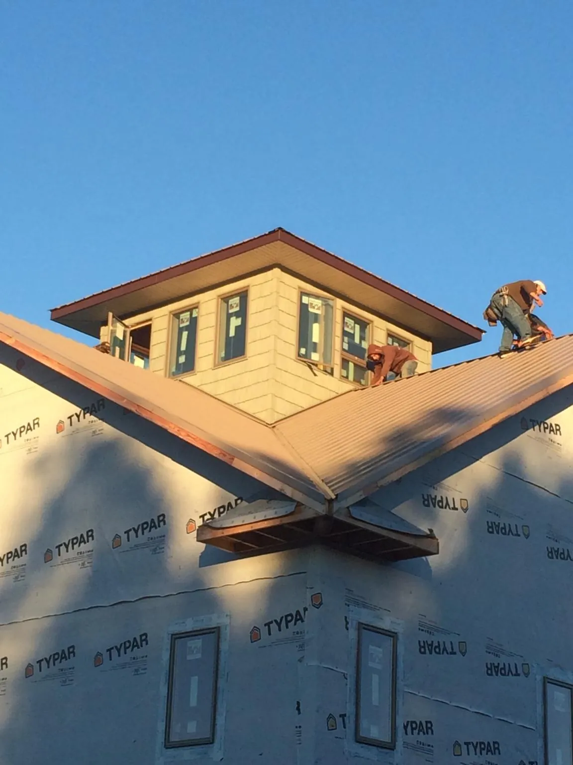 Roofers working around a rooftop cupola on a new metal roof at sunset — Roof Waterproofing in Methuen by Roofing Brothers